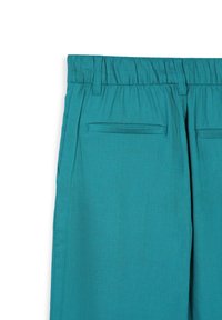 Pantaloni intessuti color turchese con vita elastica, dotati di due tasche posteriori e una texture liscia. Il design è semplice e funzionale.