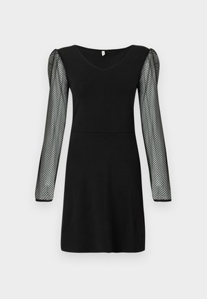 Svart kjole med V-hals og gjennomsiktige lange ermer med små svarte prikker, knelengde med en tettsittende midje.