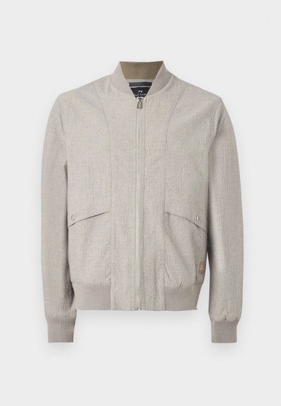 Veste bomber beige clair avec fermeture éclair à l'avant, col, poignets et bas côtelés, et deux poches à rabat pressionnées sur le devant.