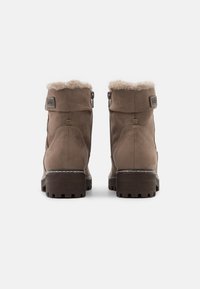 Stivali alla caviglia in suede marrone con una morbida fodera in pelliccia, cerniere laterali e suole in gomma testurizzata. Presentano cuciture sottili e un'etichetta di marca.