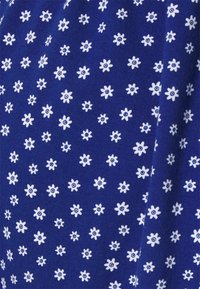 Mörkblått tyg med ett fint mönster av små vita blommor, var och en med en blå mitt. Mjuk textur, jämnt fördelat blommönster över tyget.