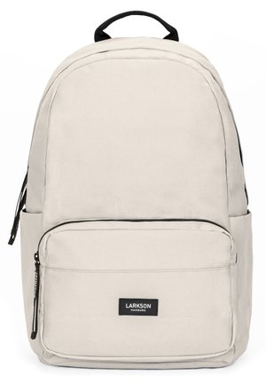 Lys grå rygsæk med et glat stof, rund form, frontlomme med lynlås og et sort mærke. Har dobbelt sidelommer og sorte detaljer.