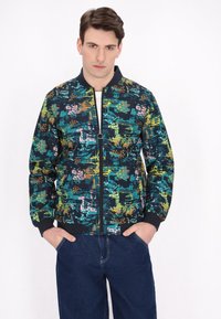 Jachetă bomber din țesătură bleumarin cu modele abstracte colorate. Are manșete ribă și închidere cu fermoar, precum și două buzunare laterale.