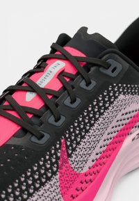 Chaussure de course Nike Pegasus présentant un dessus en mesh noir, rose et gris avec des lacets noirs, des accents moulés et un logo visible sur la languette.
