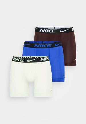 Três pares de boxers Nike: branco, azul e bordeaux, cada um com um cós preto com o logótipo da Nike. Tecido suave, design justo.