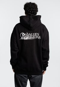 Sudadera con capucha negra que tiene un gran logo blanco con las palabras "VALORES VISIONES" y un gráfico de montañas en la parte posterior. Corte clásico y holgado, textura suave.