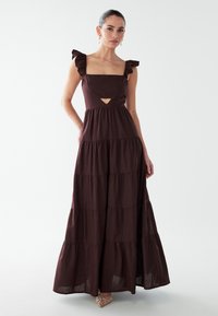 Bordeauxrode maxi-jurk met gerimpelde bandjes, vierkante halslijn en een uitsnijding bij de taille. Gelaagd ontwerp met een vloeiende silhouet en gestructureerde stof.