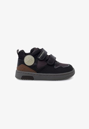 Sneaker neri per bambini con doppi cinturini in Velcro, tomaia in tessuto testurizzato, suola in gomma grigia e un accento marrone sul tallone.