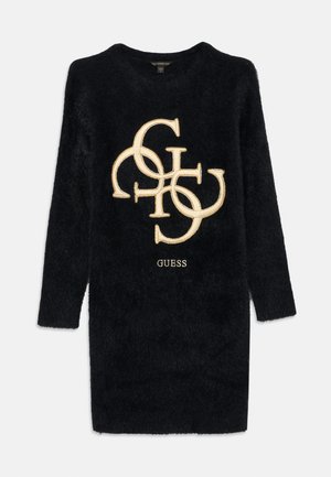 Svart langermet fuzzy kjole med store gullbroderte sammenflettede bokstaver og "GUESS"-logo på fronten.