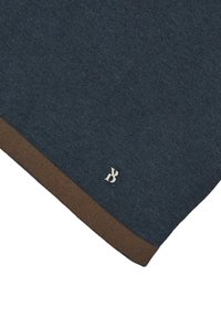 Bufanda de punto azul oscuro con un bordado marrón y un logo plateado en la esquina inferior. Textura suave, diseño rectangular.