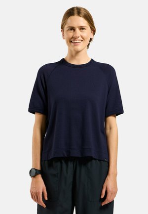 Top corto a maniche corte blu navy con un motivo a nido d'ape testurizzato e maniche raglan. Abbinato a pantaloni neri larghi e un orologio da polso.