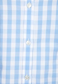 Ljusblå och vit rutig skjorta med en knappstängning, vita plastknappar och en mjuk tygtextur.