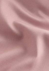 Miękka różowa tkanina o delikatnej, tkanej fakturze i łagodnych fałdach, tworzących gładkie, falujące wzory.