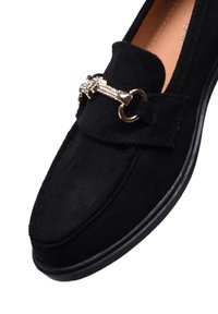 Mocassini in suede neri con un accento di catena in tono oro e strass, punta tonda e suola in gomma nera.