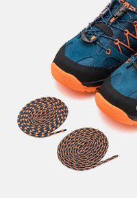 Modré a černé outdoorové boty s oranžovými akcenty, s texturovaným svrškem a kulatými tkaničkami v modré a oranžové barvě.
