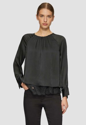 Zwarte blouse met lange mouwen, geplooide textuur, ronde halslijn en kantafwerking aan de zoom, gecombineerd met een donkere broek.