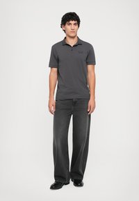Gray polo shirt with short sleeves and a small logo on the chest, paired with wide-leg gray jeans and black shoes. Simple, casual design.