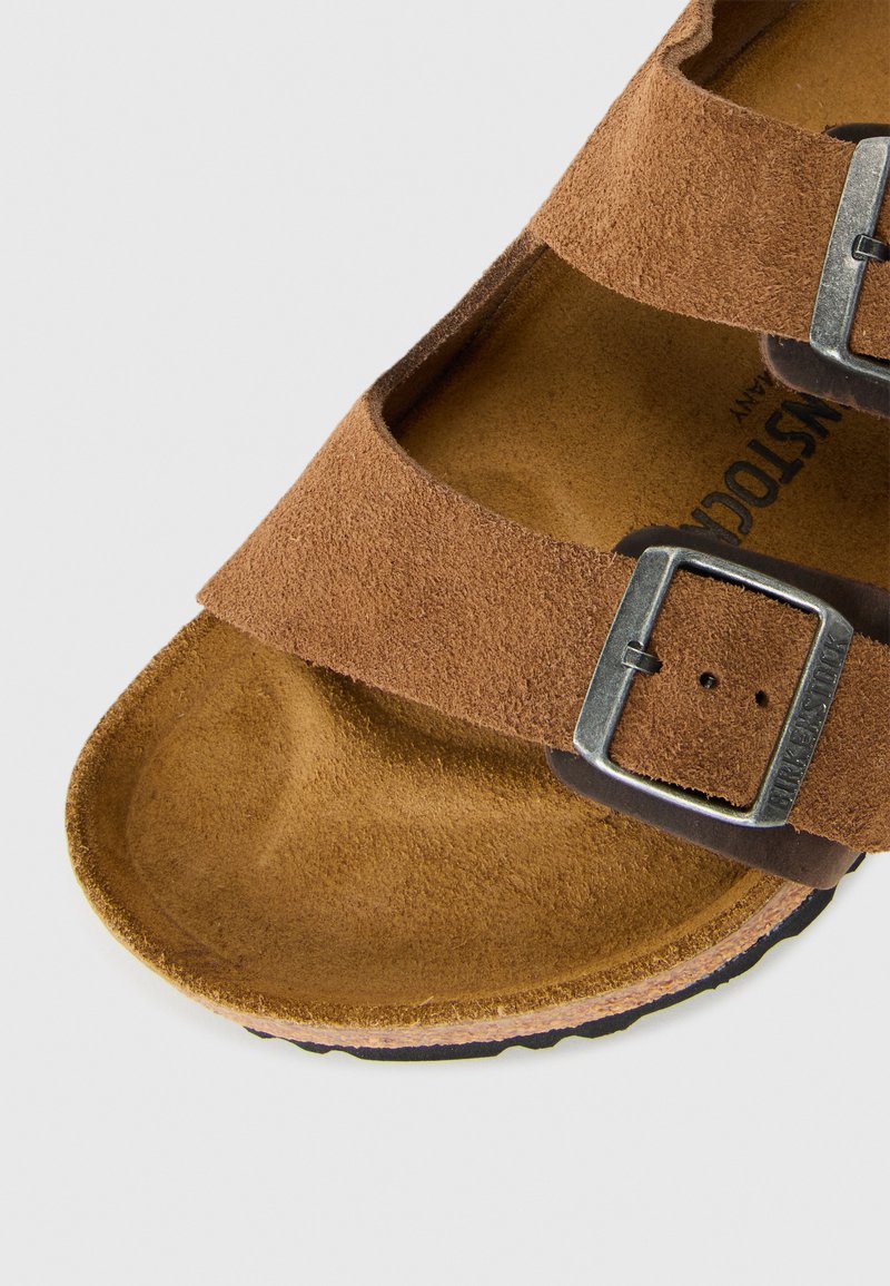 Sandal in suede marrone con due fibbie regolabili e plantare sagomato, progettato per comfort e uso casual.