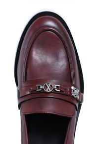 Mocasines de cuero burdeos con detalles de hardware plateado, que presentan una banda ancha en la parte superior y una puntera redondeada para un diseño clásico.