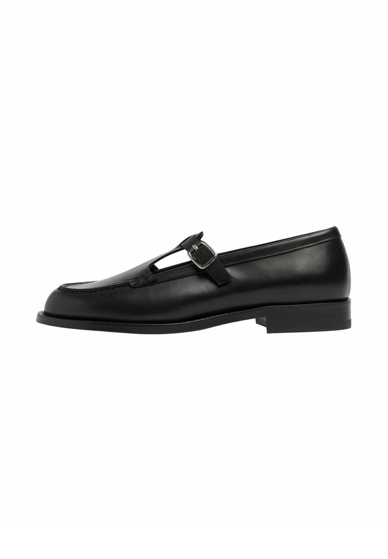 Mocassino nero in pelle con design a T e dettaglio con fibbia, suola piatta, texture liscia e accenti cuciti lungo i bordi.