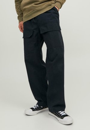 Pantaloni cargo navy con più tasche, design a gamba larga, realizzati in tessuto leggero. Abbinati a sneaker nere con lacci bianchi.
