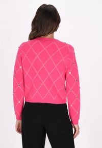 Maglione rosa lavorato a maglia con motivo a diamante e bottoni decorativi sulle maniche. Il design presenta un taglio cropped e un orlo a coste.
