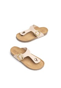 Sandali in suede beige con un anello per le dita e suola piatta in sughero. Presentano una fibbia dorata e un logo in rilievo sulla soletta.