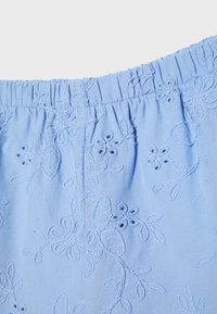 Tissu bleu clair avec ceinture élastique présentant des motifs floraux et feuilles brodés avec un fil assorti.