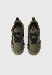 Sneaker sintetiche verdi con accenti neri, suola arrotondata, imbottitura testurizzata e lacci neri. Presentano linguette con marchio sulla lingua.