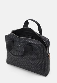 Black patterned tote bag, featuring a zippered opening, dual handles, and an interior pocket. Made from durable material with a smooth texture.