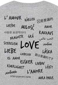 T-shirt grigia con la parola "LOVE" in evidenza in nero, circondata da traduzioni in varie lingue, con stili di carattere differenti.