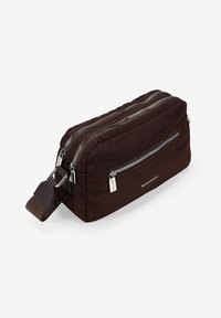 Bolsa de aseo de tela marrón con dos cremalleras plateadas, una correa lateral y un patrón cosido. Presenta un logo en la parte frontal. Forma rectangular.