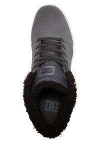 Šedé semišové skateboardové topánky s textúrovaným povrchom, čiernou fleecovou podšívkou, šedými šnúrkami a bielou gumovou podrážkou; obsahujú logo na jazyku.