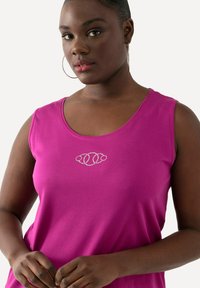 Fuchsia mouwloos top gemaakt van zacht materiaal, met een decoratief rhinestone ontwerp bij de halslijn. Soepele textuur, ronde hals.