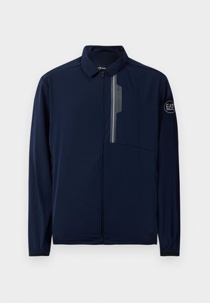 Giacca blu navy con colletto, zip frontale, tasca sul petto e dettaglio del logo sulla manica. Realizzata in un tessuto leggero e liscio.