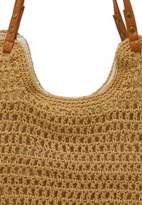Vävd beige virkade tote-väska med texturerad yta, med bruna läderaxelremmar och mässingsdetaljer vid fästpunkterna.