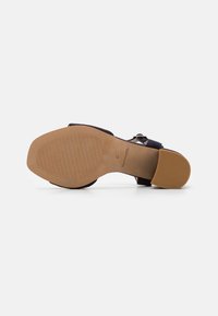 Marinblå sandal med texturerad ovandel, justerbart spänne och en tanfärgad gummisula med mönstrat mönster för bra grepp. Storlek 37.