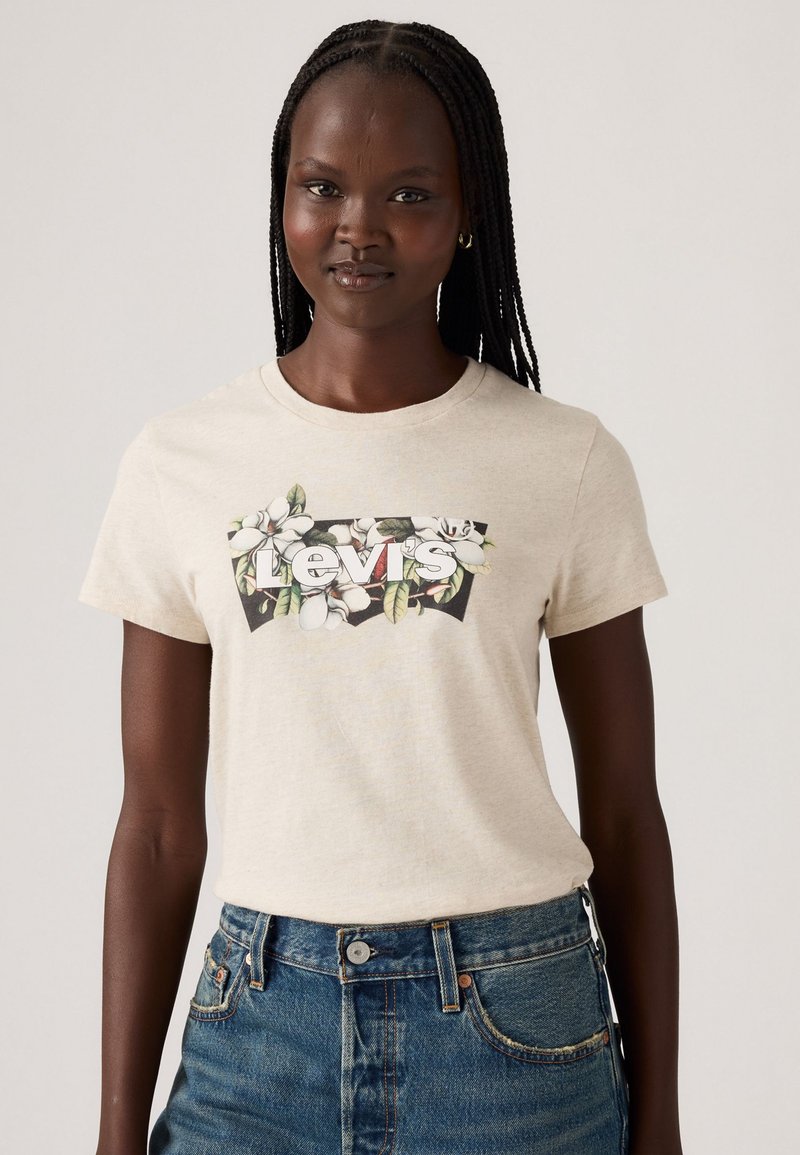 Kremowa bawełniana koszulka z floralnym motywem i napisem "Levi's" na środku, w zestawie z niebieskimi szortami z wysokim stanem.