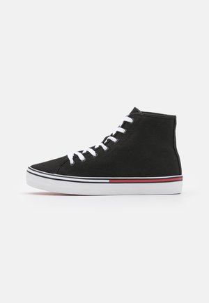 Sort højt sneakers med hvide snørebånd og en hvid sål med sorte og røde striber langs kanten, sidevisning på ensfarvet baggrund.