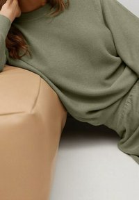 Olijfgroen geribbeld sweater gemaakt van zacht materiaal, met een comfortabele pasvorm en ronde halslijn, gecombineerd met een neutrale, gladde afwerking.