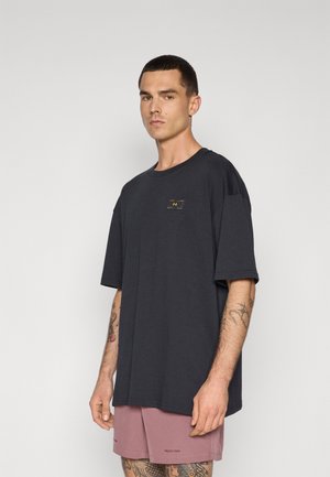 Sort kortærmet t-shirt lavet af bomuld, med et lille gult logo patch på brystet og en løs, afslappet pasform.