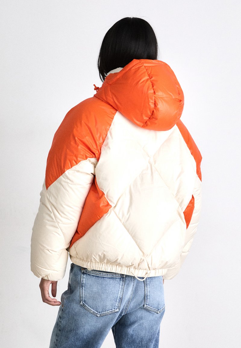 Giacca imbottita con cappuccio, con un motivo a diamante arancione e crema, orlo elasticizzato e una finitura liscia e lucida.