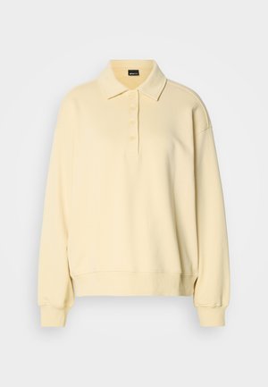 Φούτερ τύπου πόλο σε μαλακό κίτρινο χρώμα, με γιακά, πεντακάμισο κουμπιών και ριμπ μανσέτες. Χαλαρή, άνετη γραμμή με απαλή υφή.