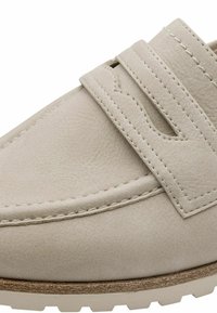 Light beige leather shoe with a rounded toe, featuring dual strap accents and visible stitching, set on a textured rubber sole.