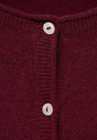Burgundy stickad cardigan med rund hals, texturerad tyg och tre pärlemorskinnknappar längs framtill.