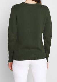 Suéter de punto verde oliva con un yugo texturizado, puños y dobladillo acanalados, y patrón de punto abierto en las mangas. Vista trasera, sin logotipos visibles.