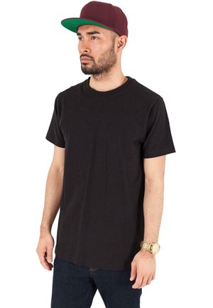 Svart bomull T-skjorte med korte ermer, rund hals, brukt sammen med mørkeblå jeans. En burgunder caps og gullklokke er synlige.