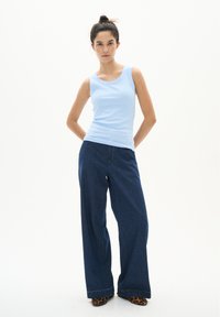 Heled sinine ribadega tank top, mis on paari pandud tume siniste laia säärega teksade ja loomaprindiga kingadega. Lihtne disain, pehme tekstuur ja mugav lõige.