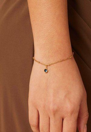 Gouden kettingarmband met een kleine, ronde, donkerblauwe edelsteen hanger. Het ontwerp van de ketting is delicaat met een gladde textuur.