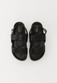 Sandalias negras de material sintético, con dos correas anchas y una hebilla ajustable. Plantilla contorneada con una textura suave.